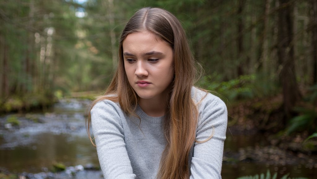 Девушка сидит в лесу одна
